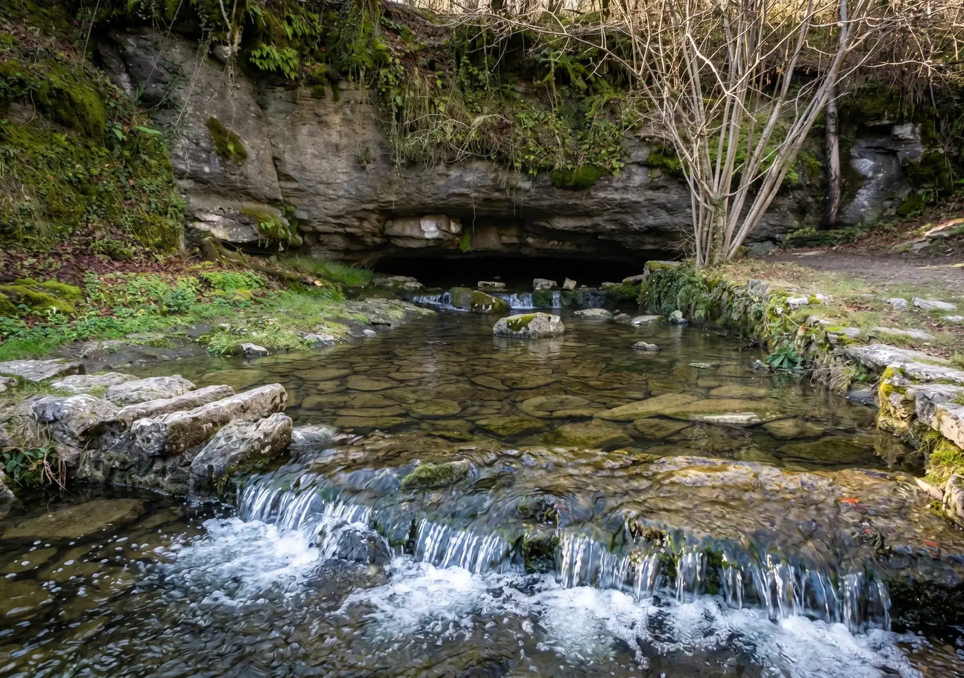 Surgencia de Fuente Santiago: el agua sale de una boca baja en la roca y baja en pequeños saltos